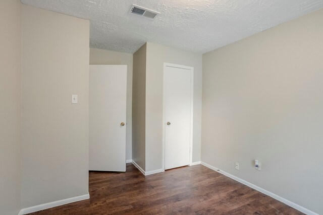 empty room featuring baseboards, a textured ceiling, wood finished floors, and visible vents