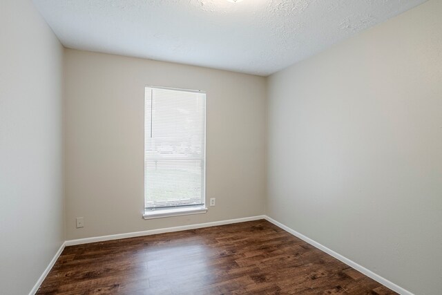 empty room featuring dark wood-type flooring and baseboards