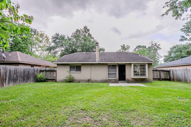 rear view of property with a fenced backyard, a patio, a lawn, and brick siding