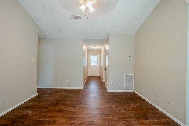 empty room with visible vents, a ceiling fan, a textured ceiling, and wood finished floors