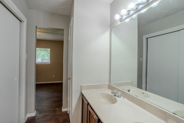 bathroom with vanity, baseboards, a textured ceiling, and wood finished floors