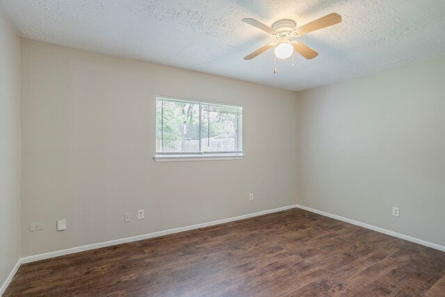 spare room featuring a ceiling fan, baseboards, and dark wood-style floors