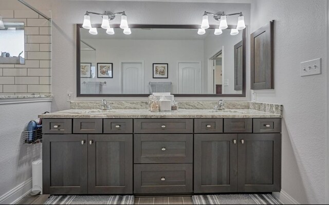 full bathroom with double vanity, baseboards, and a sink