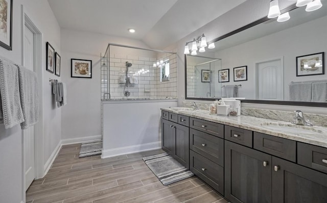 bathroom featuring double vanity, walk in shower, a sink, and wood finished floors