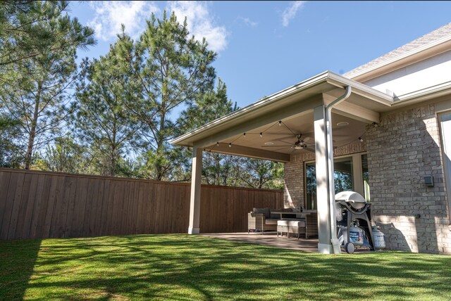 view of yard with an outdoor living space, ceiling fan, fence, and a patio