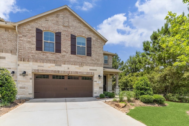 26 Heirloom Garden Pl, Magnolia, TX 77354 - view of front facade with concrete driveway, an attached garage, brick siding, and stone siding