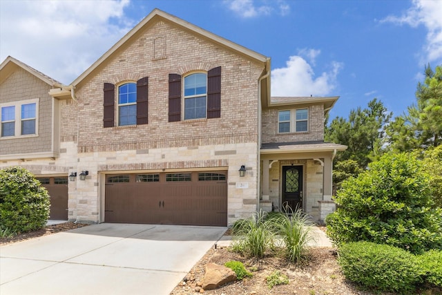 26 Heirloom Garden Pl, Magnolia, TX 77354 - view of front of house featuring a garage, brick siding, driveway, and stone siding