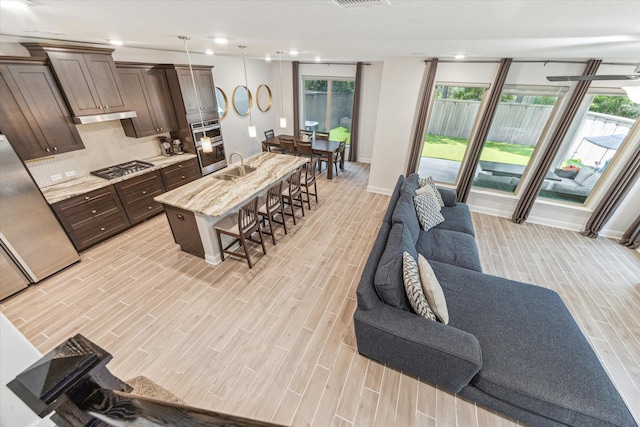 26 Heirloom Garden Pl, Magnolia, TX 77354 - kitchen with open floor plan, a kitchen bar, light wood-style flooring, dark brown cabinets, and recessed lighting