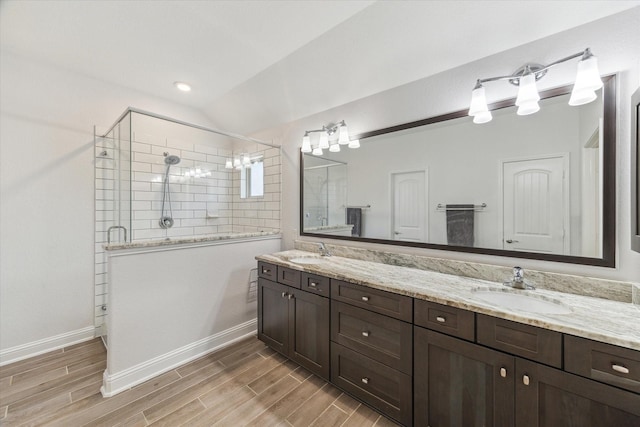 26 Heirloom Garden Pl, Magnolia, TX 77354 - bathroom with double vanity, a tile shower, wood finished floors, baseboards, and vaulted ceiling