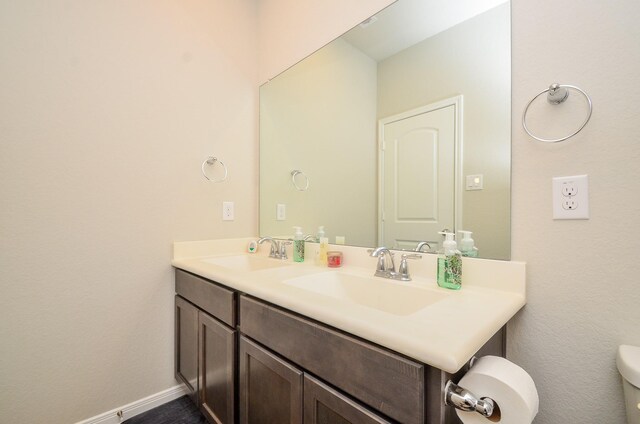 12630 Beddington Ct, Tomball, TX 77375 - bathroom featuring double vanity, toilet, baseboards, and a sink