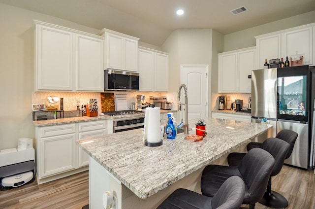 12630 Beddington Ct, Tomball, TX 77375 - kitchen featuring white cabinets, stainless steel appliances, decorative backsplash, and light wood-style flooring