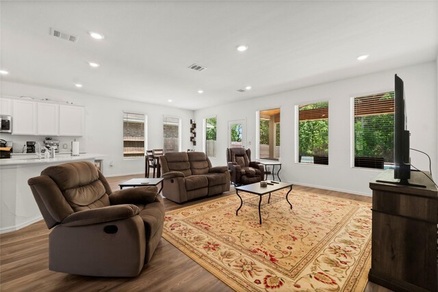 living area with recessed lighting, baseboards, visible vents, and wood finished floors