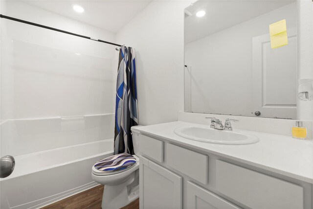 bathroom featuring vanity, wood finished floors, toilet, recessed lighting, and shower / tub combo