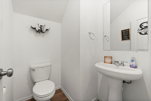 half bathroom with toilet, baseboards, wood finished floors, and lofted ceiling
