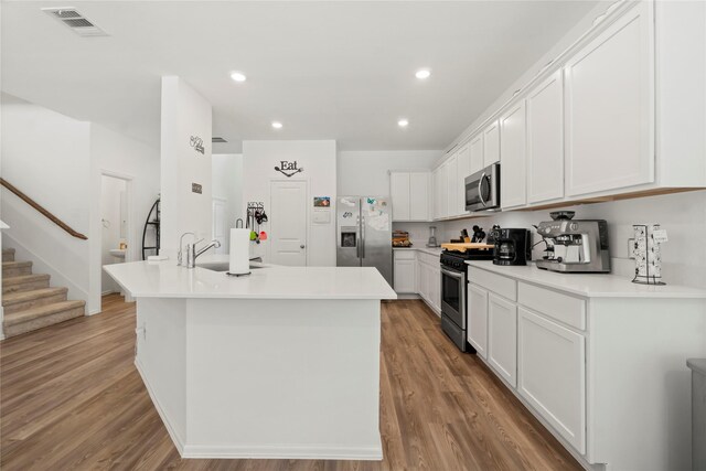 kitchen featuring stainless steel appliances, visible vents, white cabinetry, and light wood-type flooring