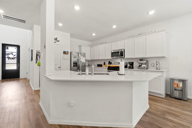 kitchen with visible vents, appliances with stainless steel finishes, light wood-type flooring, a sink, and light countertops
