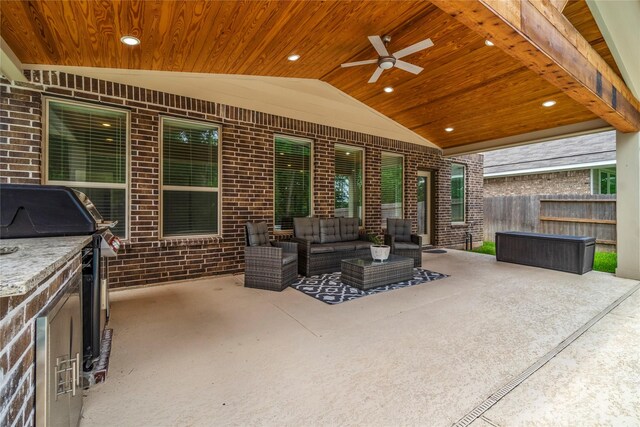 view of patio featuring area for grilling, ceiling fan, fence, an outdoor hangout area, and an outdoor kitchen