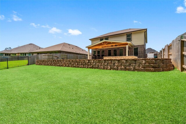 rear view of house featuring a fenced backyard, a yard, and brick siding