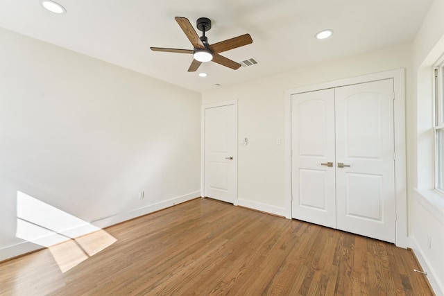 unfurnished bedroom featuring baseboards, a closet, recessed lighting, and wood finished floors