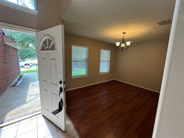 foyer entrance featuring visible vents, plenty of natural light, and an inviting chandelier