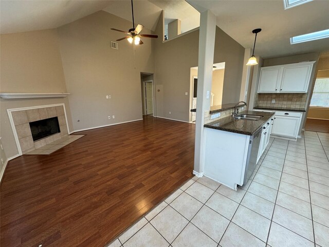 kitchen featuring ceiling fan, a sink, light wood finished floors, open floor plan, and white cabinetry
