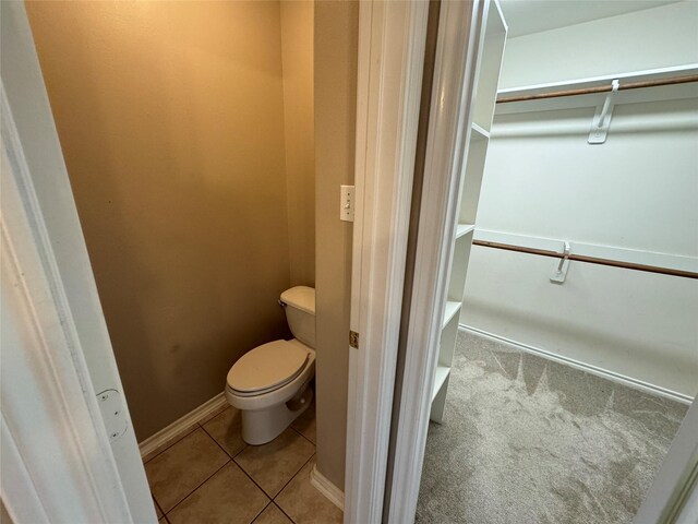 bathroom with tile patterned flooring, baseboards, and toilet