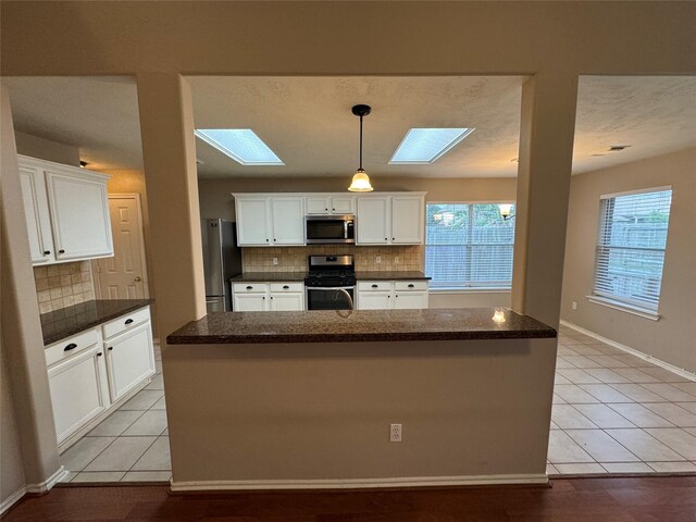 16407 Thyme Green Ln, Cypress, TX 77433 - kitchen featuring stainless steel appliances, a skylight, tasteful backsplash, white cabinets, and light tile patterned flooring