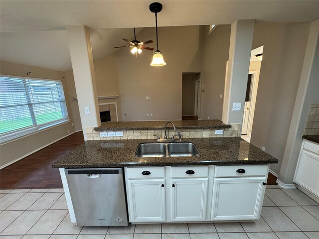 kitchen featuring ceiling fan, stainless steel dishwasher, vaulted ceiling, a sink, and light tile patterned flooring