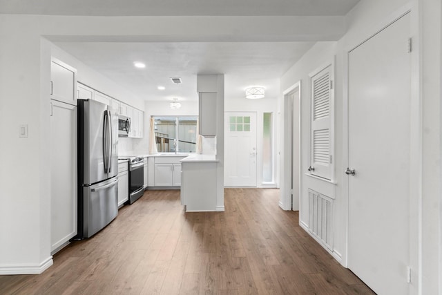 kitchen with visible vents, wood finished floors, light countertops, white cabinets, and stainless steel appliances