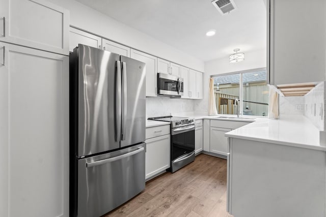 kitchen with appliances with stainless steel finishes, decorative backsplash, a sink, and visible vents