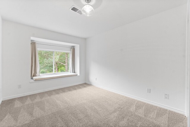 spare room with carpet floors, baseboards, and visible vents