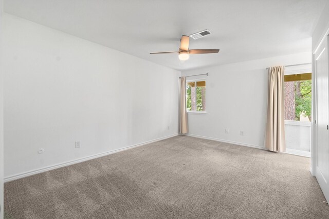 carpeted spare room with visible vents, a ceiling fan, and baseboards