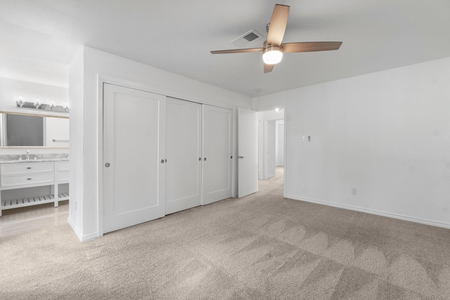 unfurnished bedroom with visible vents, a sink, baseboards, a closet, and carpet flooring