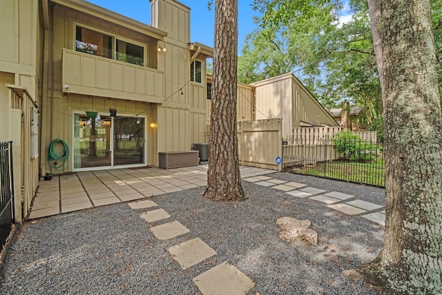 back of house featuring fence, board and batten siding, a chimney, a patio area, and central air condition unit
