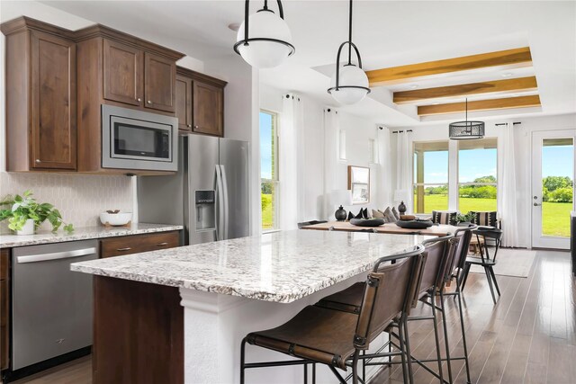 kitchen featuring backsplash, appliances with stainless steel finishes, wood finished floors, and light stone counters