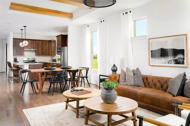 living room with a raised ceiling and light wood-style flooring