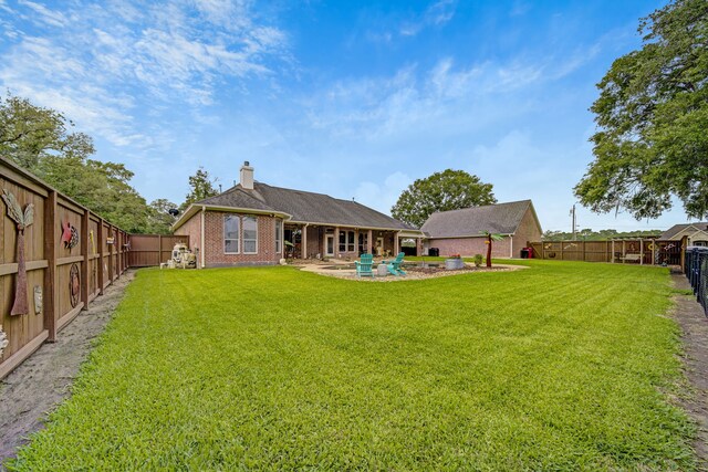 back of property featuring brick siding, a fenced backyard, a yard, and a chimney