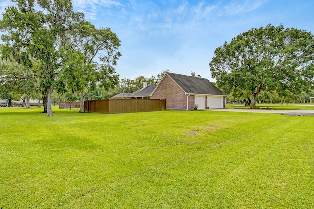 view of yard with fence, driveway, and a garage