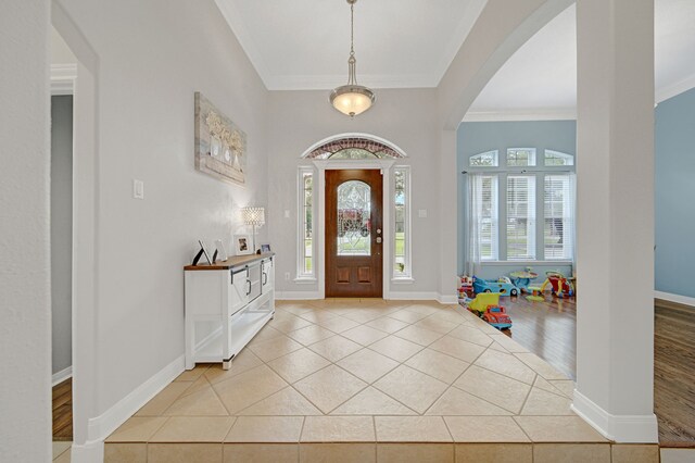 entryway with baseboards, ornamental molding, arched walkways, and light tile patterned floors