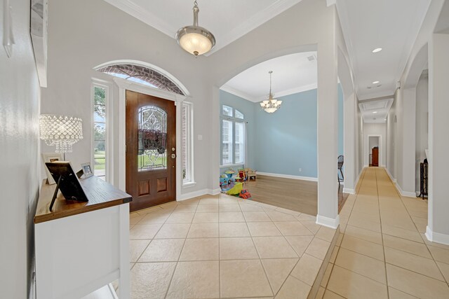 foyer with baseboards, arched walkways, light tile patterned floors, and a notable chandelier