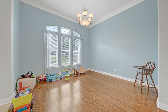 game room with an inviting chandelier, baseboards, ornamental molding, and wood finished floors