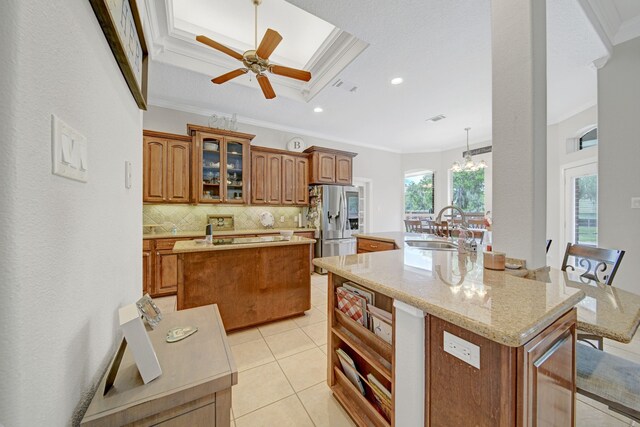 kitchen with crown molding, brown cabinetry, an island with sink, and a sink