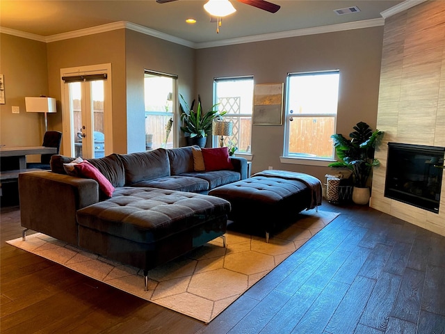 living area with a ceiling fan, visible vents, crown molding, a fireplace, and hardwood / wood-style floors