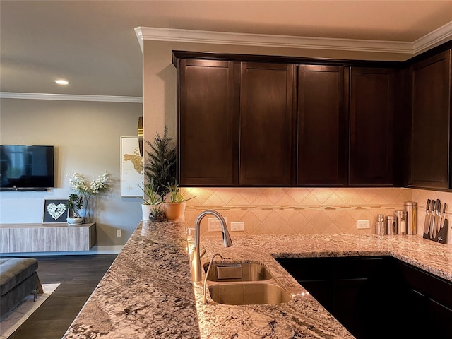 kitchen featuring crown molding, light stone countertops, dark brown cabinetry, and a sink