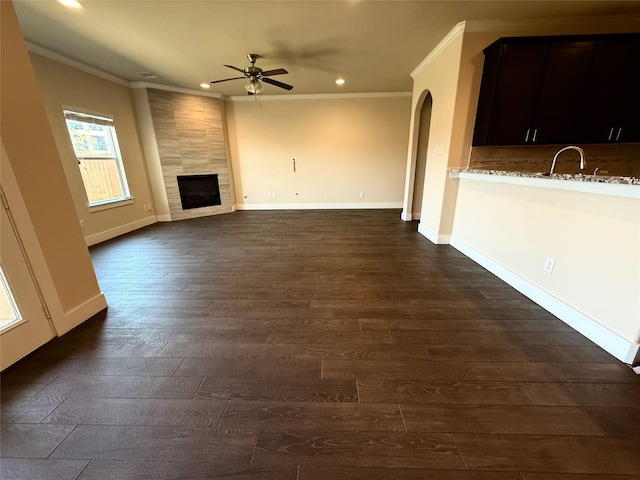 unfurnished living room with a tiled fireplace, ornamental molding, a ceiling fan, and recessed lighting