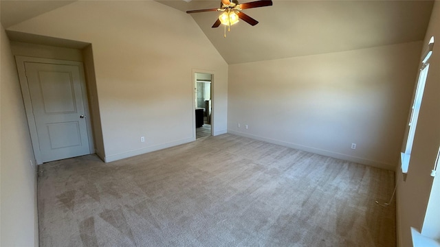 empty room with light colored carpet, ceiling fan, vaulted ceiling, and baseboards