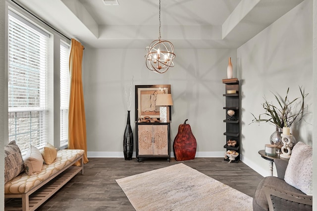 living area featuring baseboards, a chandelier, dark wood-style floors, and a raised ceiling