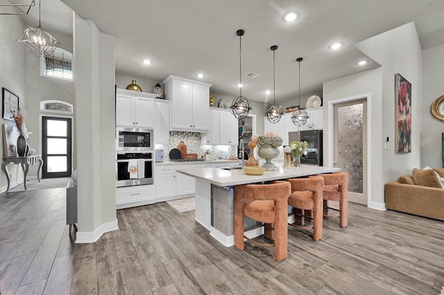 kitchen with a notable chandelier, appliances with stainless steel finishes, light countertops, baseboards, and decorative backsplash
