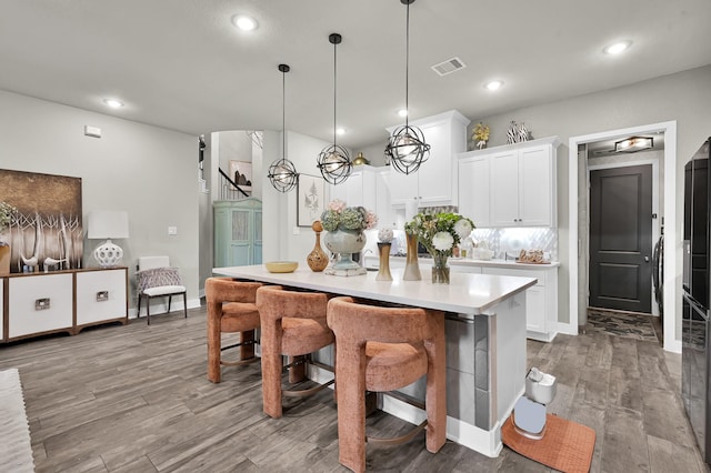 kitchen featuring visible vents, pendant lighting, wood finished floors, light countertops, and white cabinetry