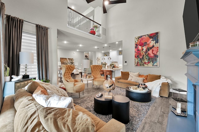 living room featuring a ceiling fan, wood finished floors, and a towering ceiling